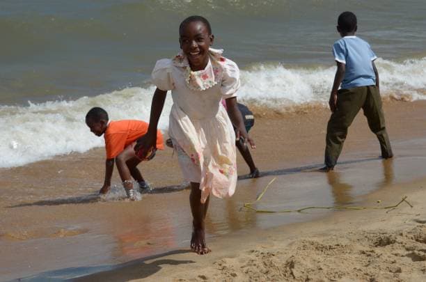 Smiling Malawian children playing and running along the sandy shore of Lake Malawi